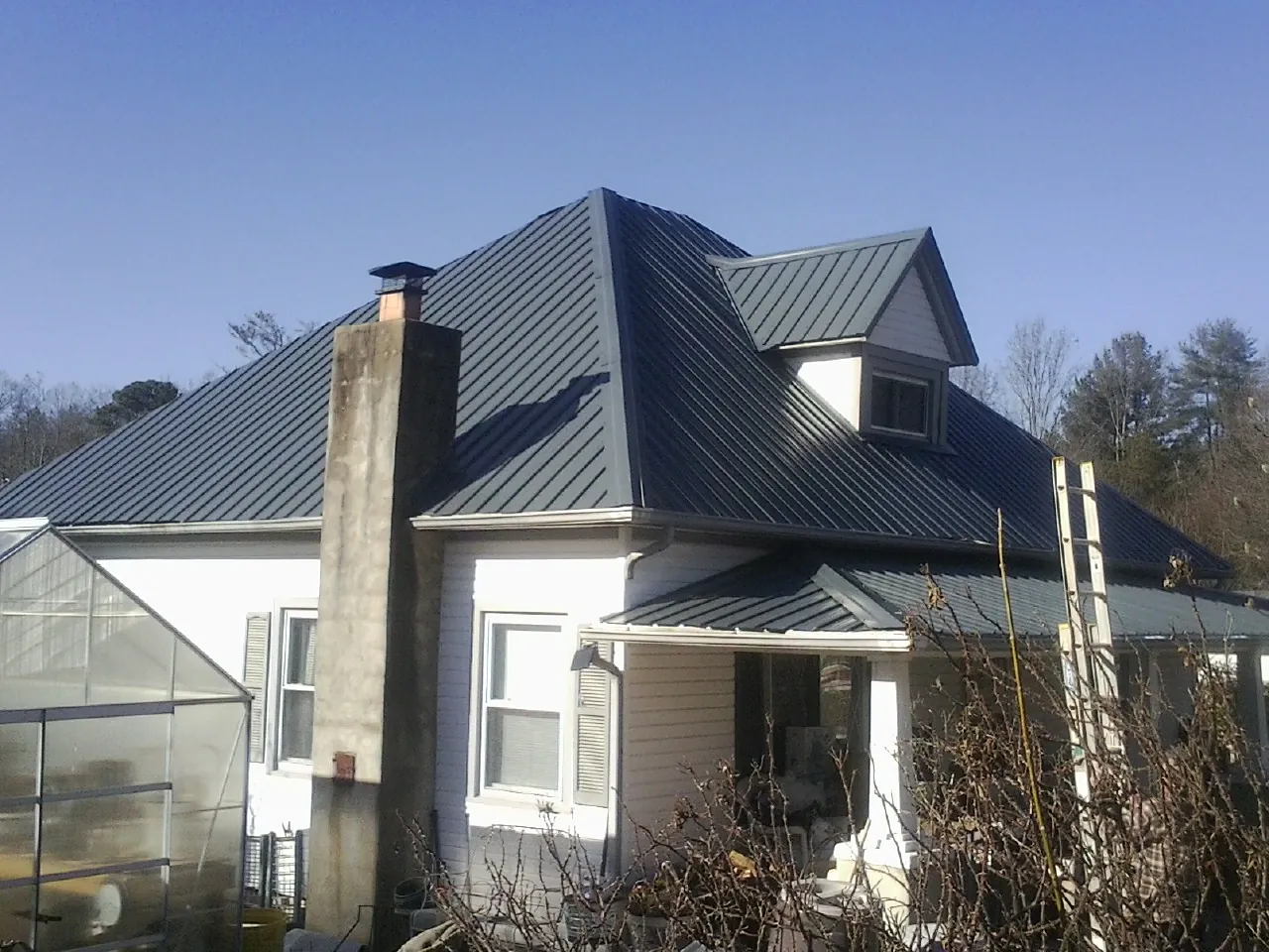 Dark blue standing seam metal roof on a white farmhouse with dormer — Slate & Tile Roof Repair by Roofing Brothers in La Jolla
