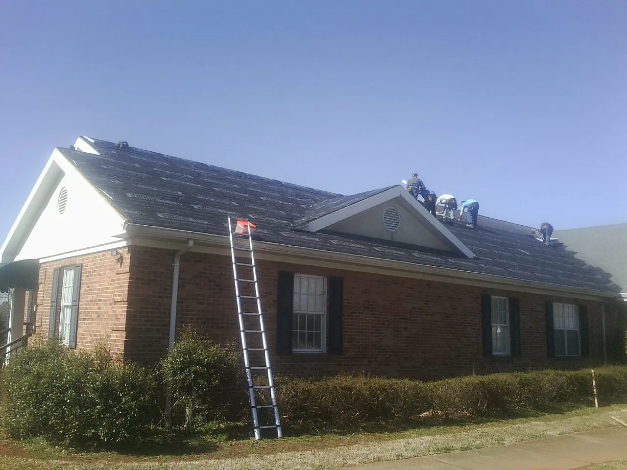 Crew tearing shingles off a brick ranch roof with a ladder set — Metal Roof Repair work by our crew in La Jolla
