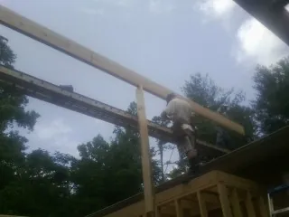 Carpenter setting a ridge beam over a new addition frame — Ice Dam Removal by Roofing Brothers in La Jolla