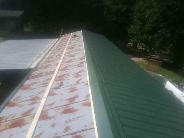 Old rusted panels beside newly installed green metal roofing — Wind Damage Roof Repair by Roofing Brothers in La Jolla