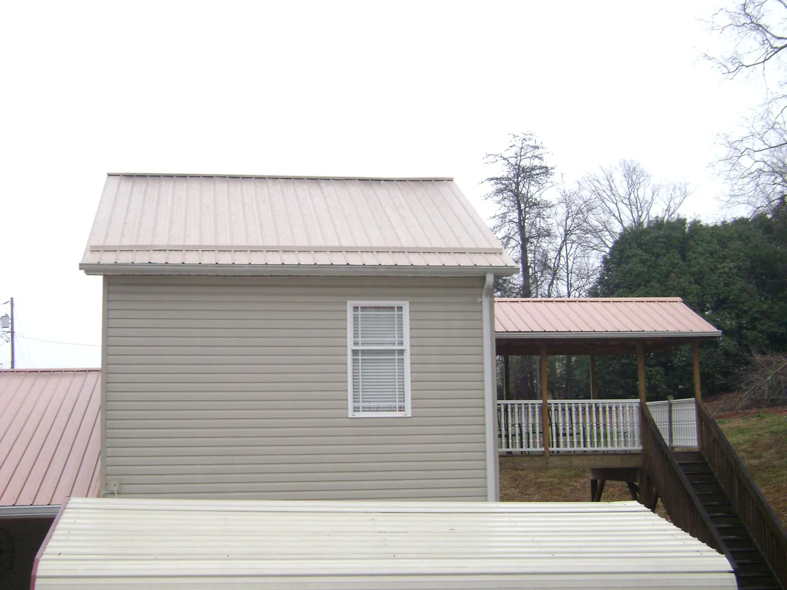 Tan metal roofs on a two story addition and attached porch, from a Roof Replacement job in La Jolla